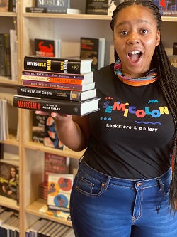 Bookseller at Semicolon Bookstore with a stack of books